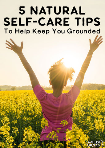 Person in a field of yellow flowers with arms raised, text reads 5 Natural Self-Care Tips to Help Keep You Grounded.