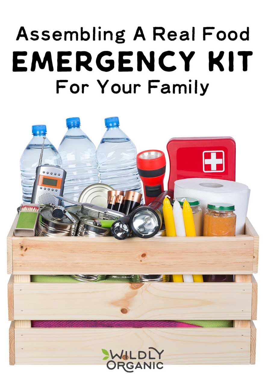 Photo of a real food emergency kit with water bottles, canned goods, flashlights, batteries, and first aid supplies in a crate