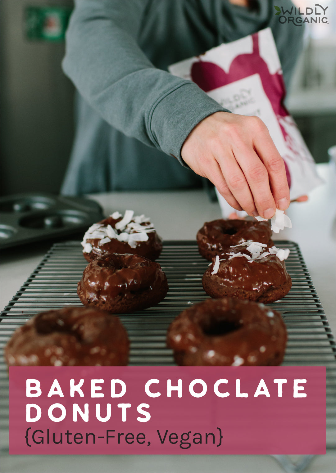 Chocolate donuts on a metal cooling rack. Person sprinkling coconut chips on top.