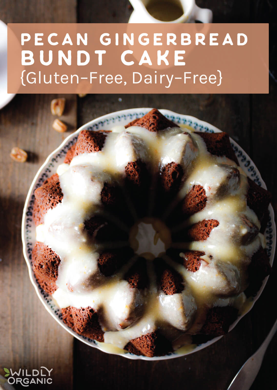 An overhead shot of a pecan ginger bundt cake with icing on a ceramic plate on a rough wooden table and pecans scattered.