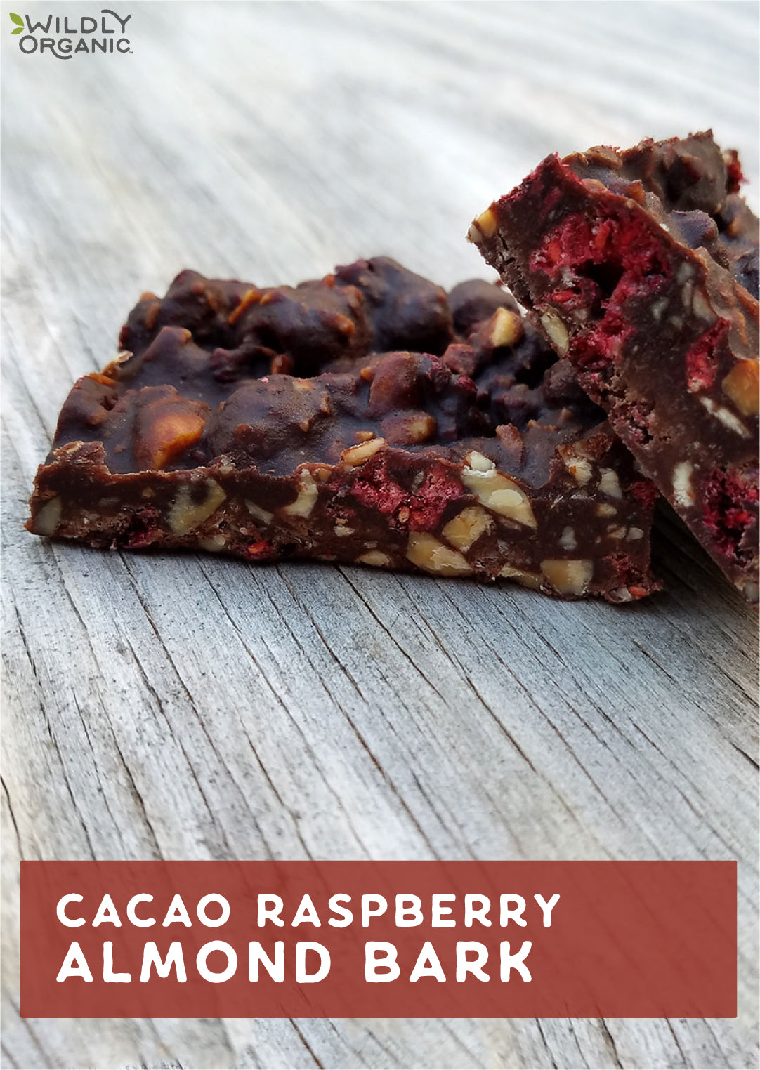 Piece of cacao raspberry almond bark on a wooden surface with logo Wildly Organic.