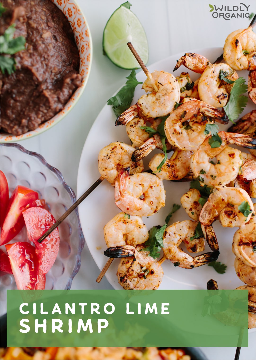 Shrimp on skewers on a white plate with other ingredients to the side.