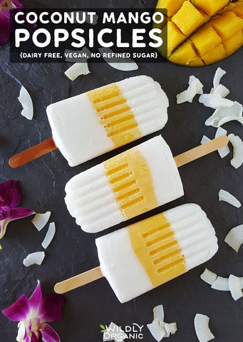Top down photo of coconut mango popsicles on a black slate board.