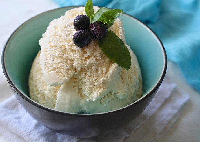 Scoops of ice cream topped with blueberries inside a blue ceramic bowl