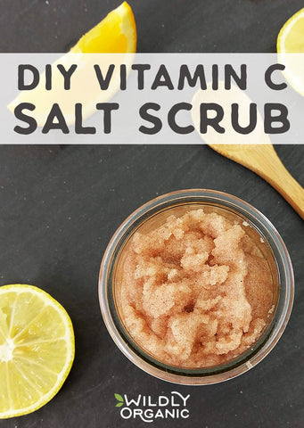 Homemade Vitamin C salt scrub in a jar, lemon slice on the side, wooden spoon, on a dark surface