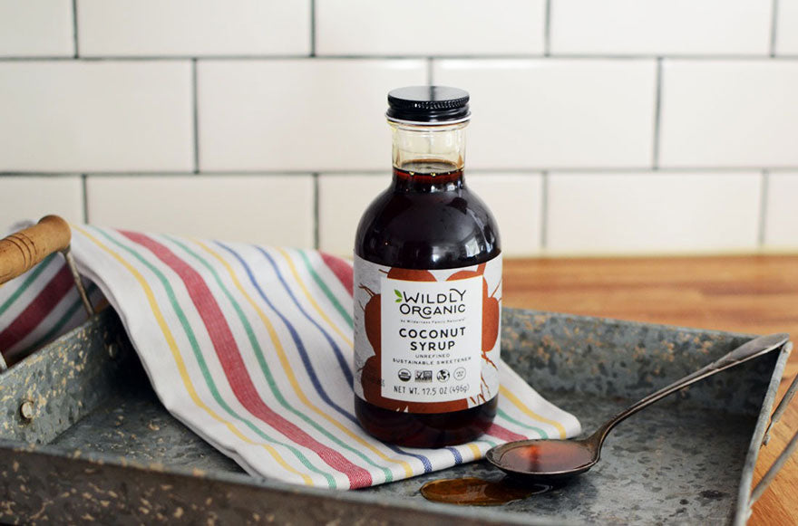Bottle of coconut syrup on a tray with a spoon, next to a striped towel