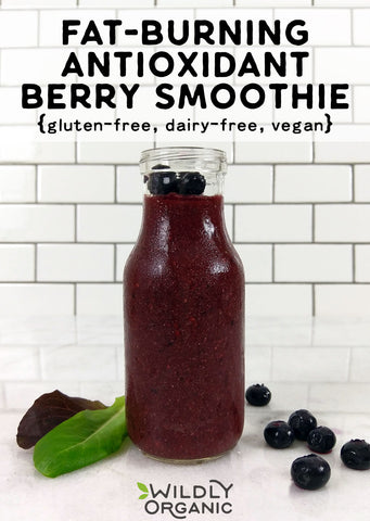 Photo of a dark berry colored smoothie in a milk bottle, blueberries are around it.