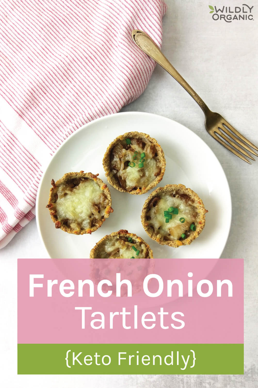 4 French onion tartlets on a white plate on a striped dishcloth.