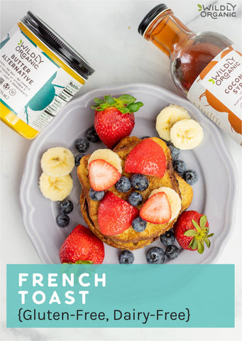 French toast covered in strawberries, blueberries, and bananas on a white plate with Wildly Organic Coconut Syrup and Butter Alternative
