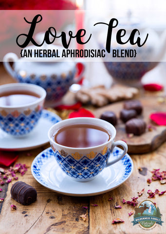 A cup of tea with Love Tea label, chocolates, and rose petals on a wooden surface.