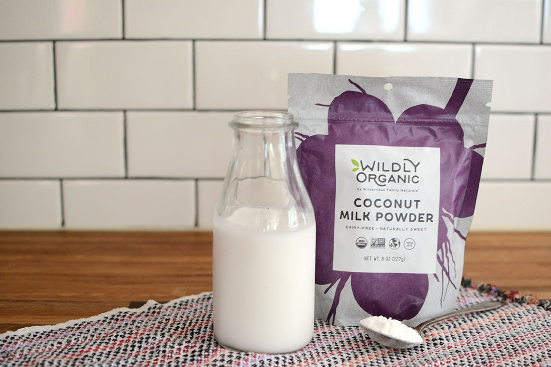 A bottle of milk beside a packet of Wildly Organic coconut milk powder on a woven mat