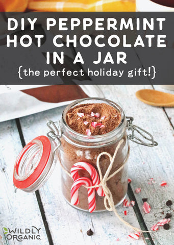 A photo of a jar of peppermint hot chocolate in a jar tied with twine and two mini candy canes with a bag of Wildly Organic Hot Chocolate Mix in the background.