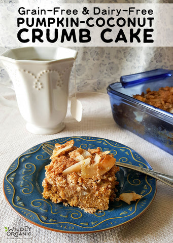 A slice of grain-free, dairy-free pumpkin-coconut crumb cake on a blue plate with a fork, next to a white mug and a baking dish.