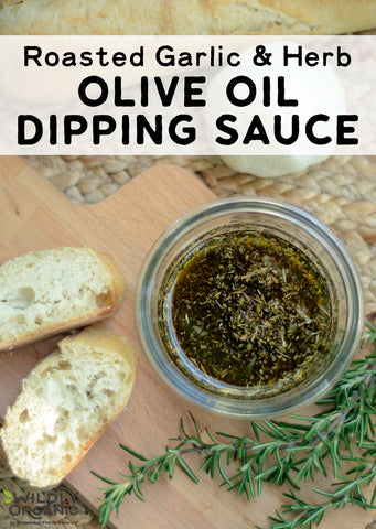 Jar of herb-infused olive oil with text Roasted Garlic & Herb Olive Oil Dipping Sauce, bread, and rosemary.