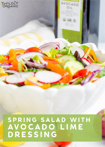 Spring salad in a white bowl with Wildly Organic Avocado Oil in the background