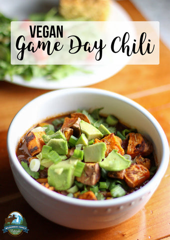 A bowl of vegan chili topped with avocado and green onions, with Vegan Game Day Chili text overlay