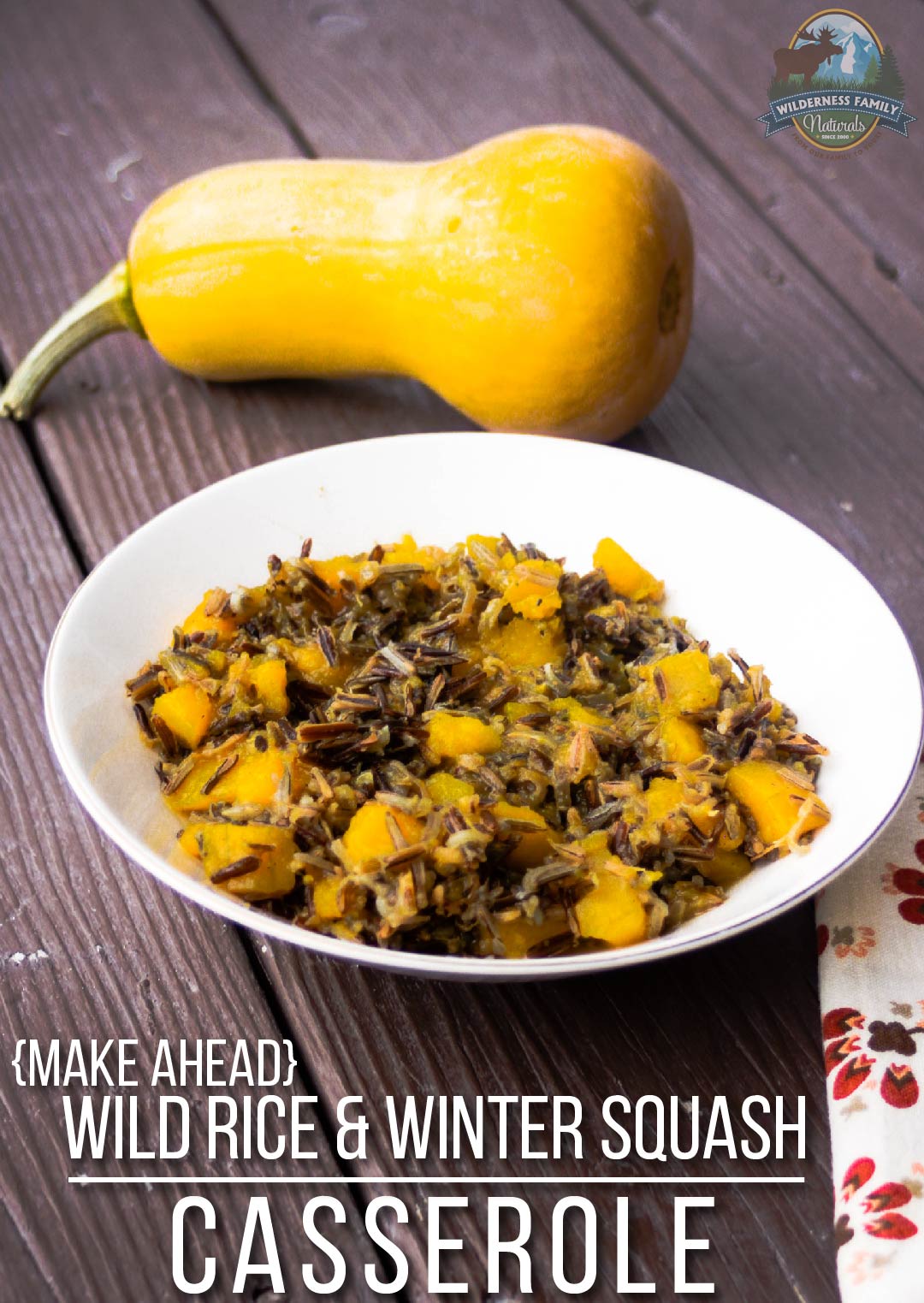 A casserole dish with wild rice and squash next to a whole butternut squash on a wooden table