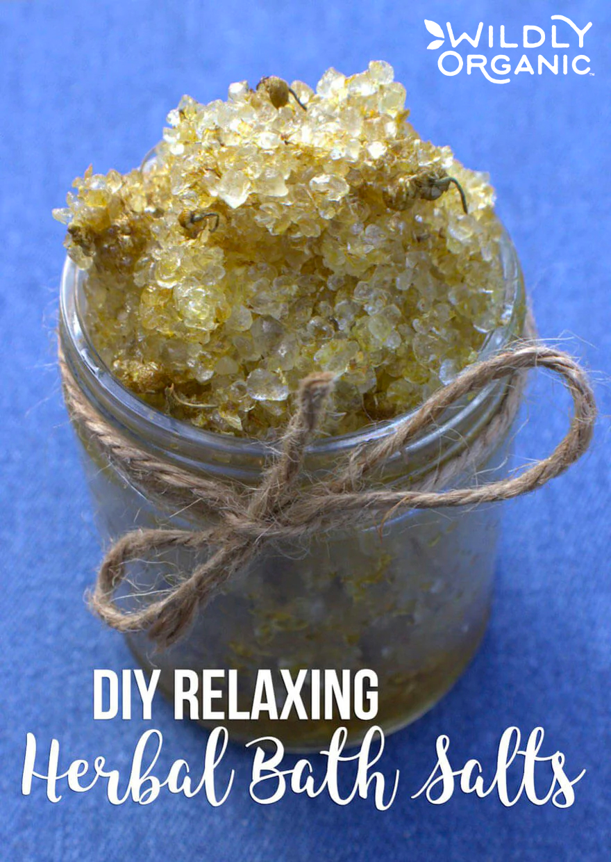 Jar of homemade herbal bath salts with twine on a blue background, labeled DIY Relaxing Herbal Bath Salts